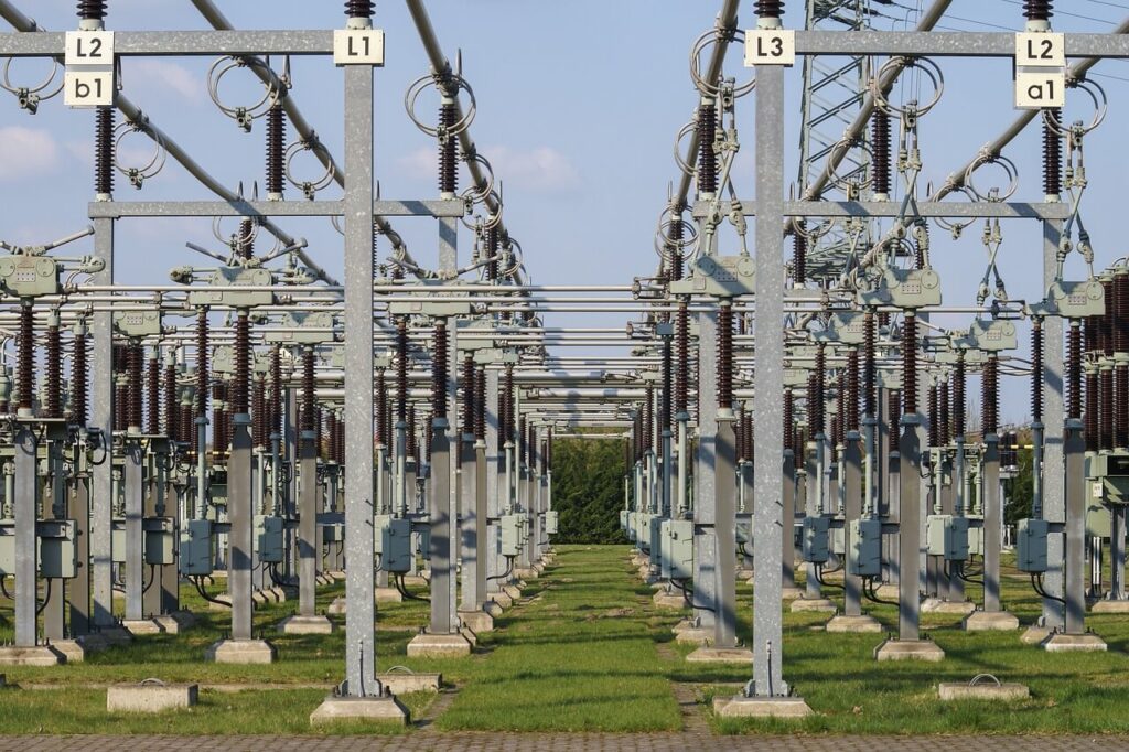 Linee elettriche ad alta tensione in una stazione di trasformazione con tralicci metallici e isolatori in ceramica.