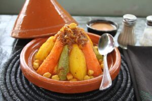 Couscous tradizionale servito in una tajine con verdure, ceci e cipolle caramellate, tipico della cucina marocchina e nordafricana.