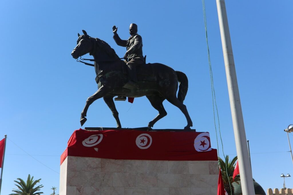 Statua equestre in Tunisia con dettagli decorativi e bandiere tunisine, contro un cielo azzurro